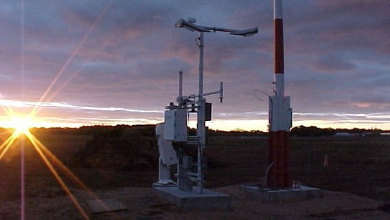 An AWOS system with the sun rising on the horizon.