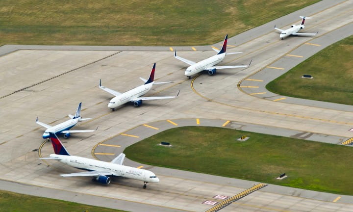 Several commercial planes lined up on a runway.