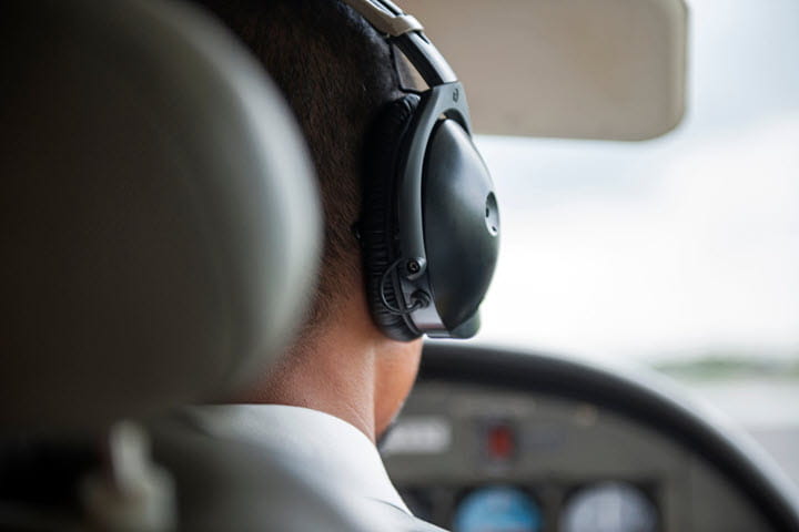 A pilot with his headset on sitting in the cockpit.