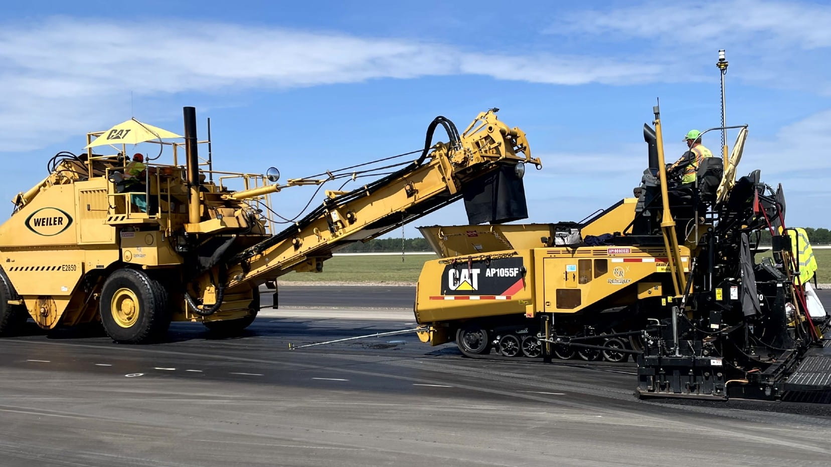 Crews lay new asphalt on a airport runway.
