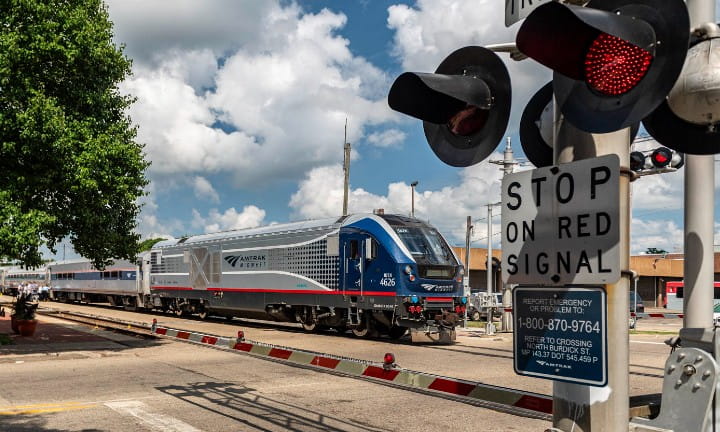 An Amtrak train at a signalized train crossing.