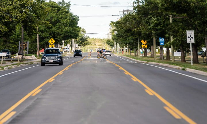 A road with a dedicated turn lane and pedestrian crossing for safety.