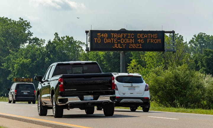 Cars on a rural road in Michigan passing a Dynamic Message Sign that reads, Don't Text and Drive.