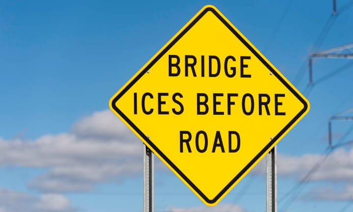 Fluorescent yellow sheeting on a Bridge Ices Before Road sign.