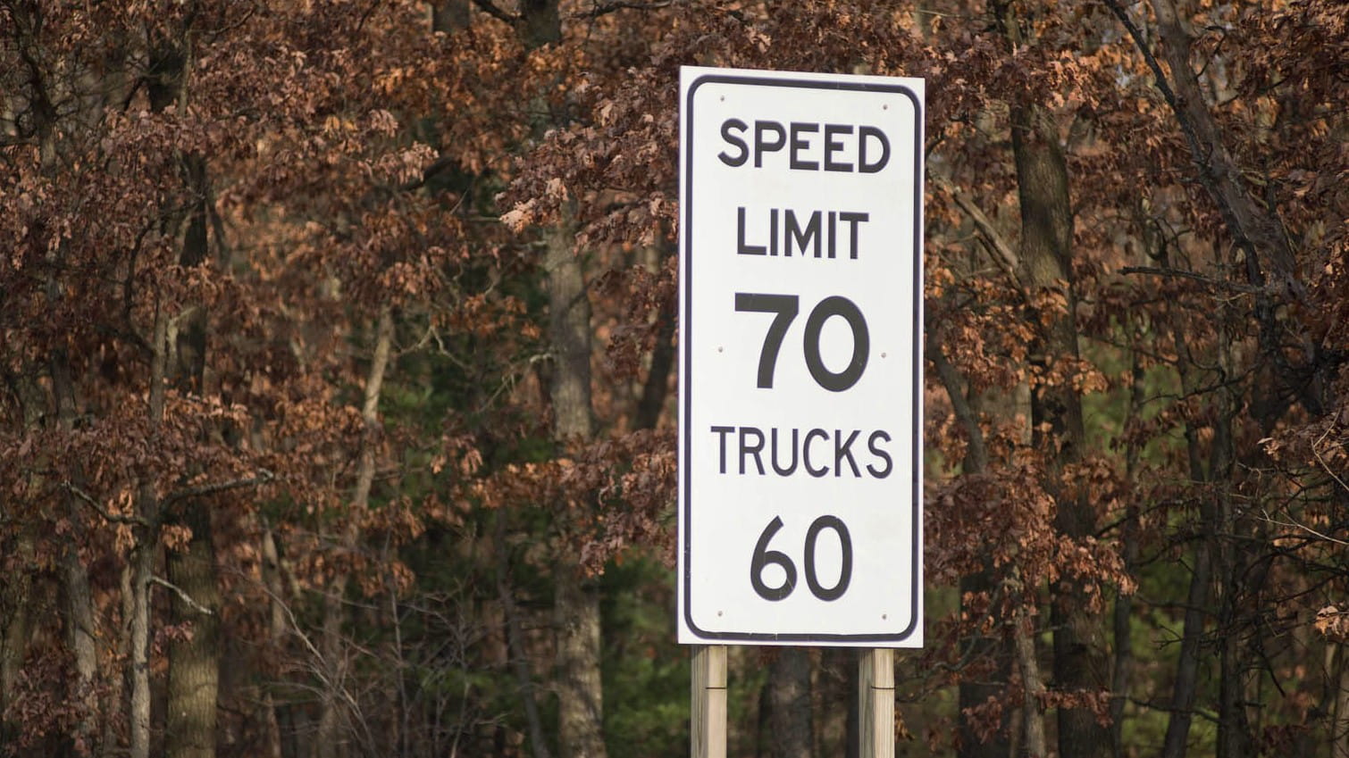A speed limit sign along a Michigan freeway indicating 70 mph for cars and 60 mph for trucks.