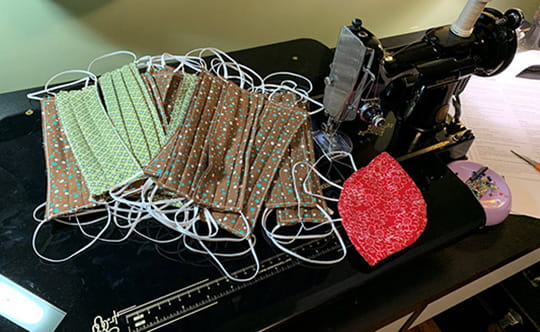 Several hand sewn rectangular cotton face masks sitting on a sewing machine