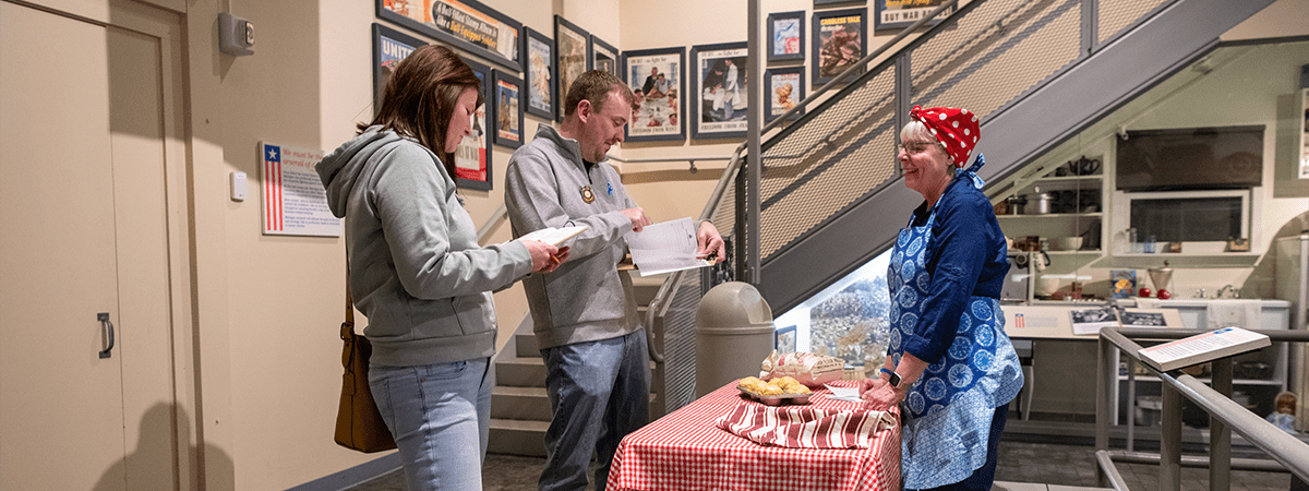 Two people talking to someone dressed in historical clothing during Mystery at the Museum.