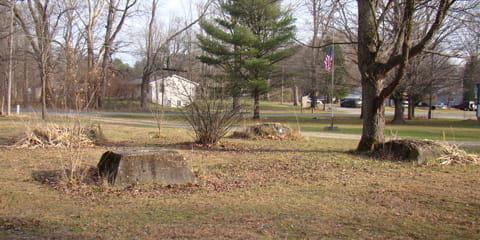 Four large cement water tower footings project about 18 inches above grass
