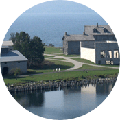Viewed from above, several historic buildings sit on a strip of land between two bodies of water.