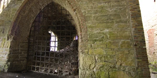 A large light-colored gothic-style brick arch with a metal gate. 