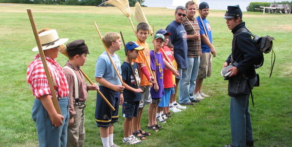 A soldier in period costume teaches drills to visitors to Fort Wilkins
