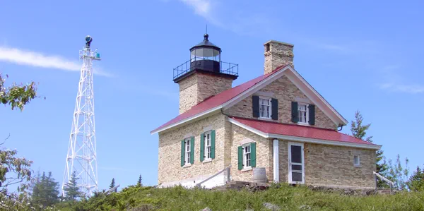 A 2-story yellow brick building with a square lighthouse tower on the front.