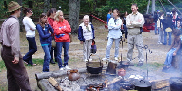 Visitors stand around a dutch over at the outdoor cooking demonstration at Hartwick Pines State Park.