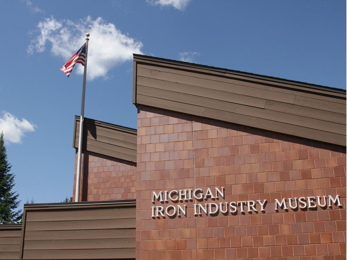 A reddish-brown brick building with a steep pitched roof and brown trim.