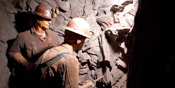 two male mannequins dressed as minors drill rock in a museum diorama.