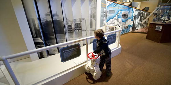 A boy looks at a large image of a freighter