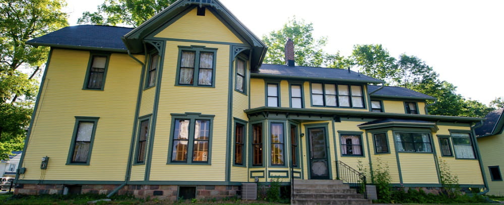 A 2-story Late Victorian home with elements of Eastlake design; yellow exterior with green trim.