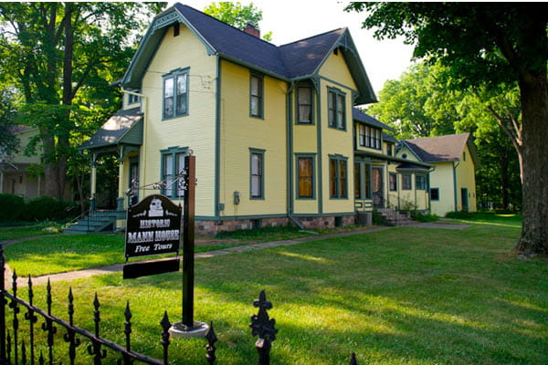 A 2-story Late Victorian home with elements of Eastlake design; yellow exterior with green trim.