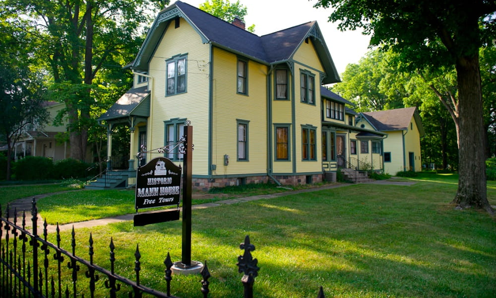 A 2-story Late Victorian home with elements of Eastlake design; yellow exterior with green trim.