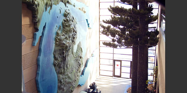 A 2-story relief map of Michigan is mounted on the wall.