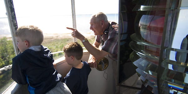 Man and children looking out at the water from the top of the tower.