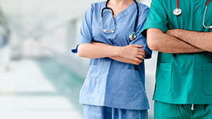 Two hospital staffs - surgeon, doctor or nurse standing with arms crossed in the hospital. 
