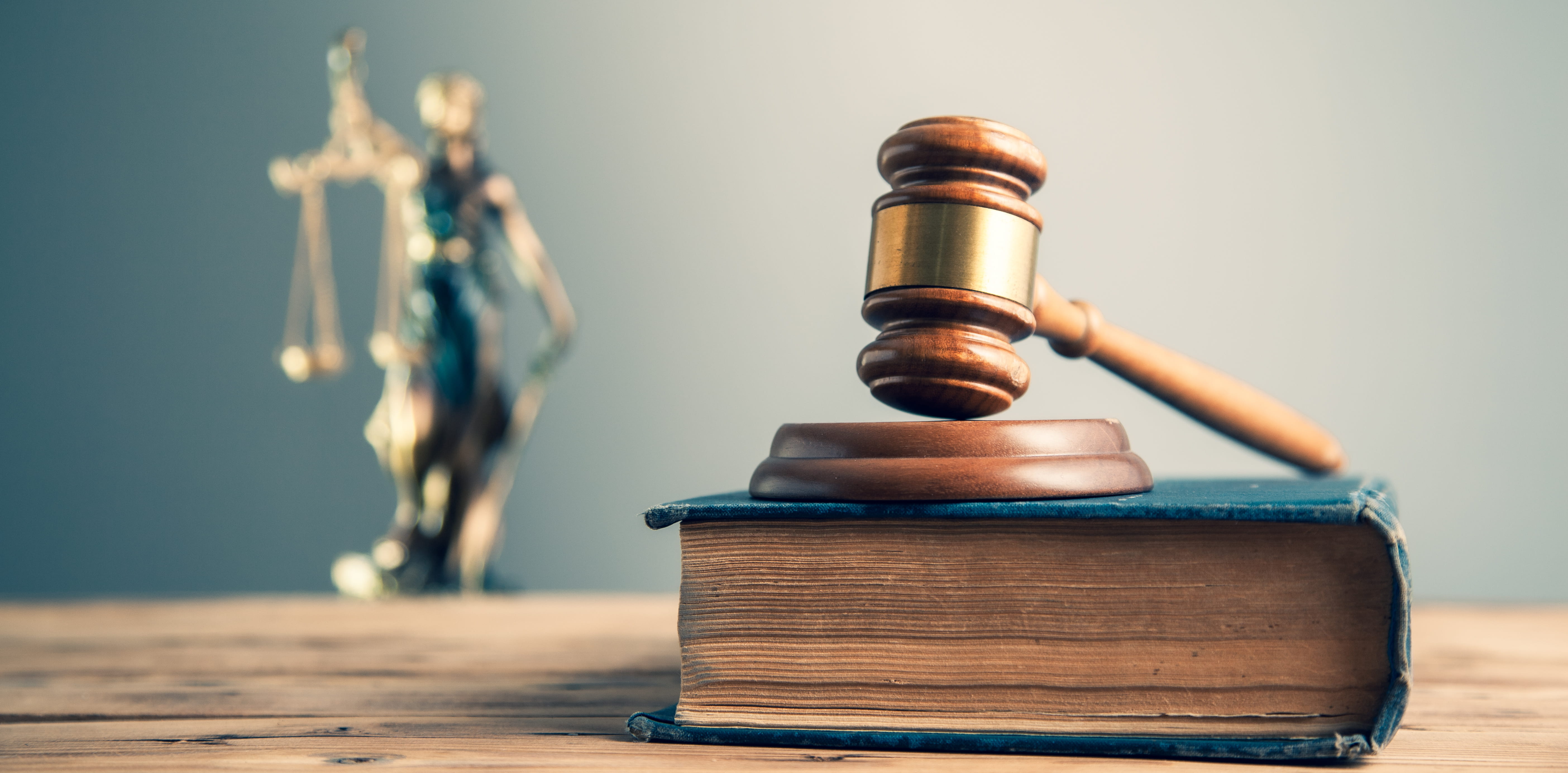 Wooden judge on book with justice lady on desk.