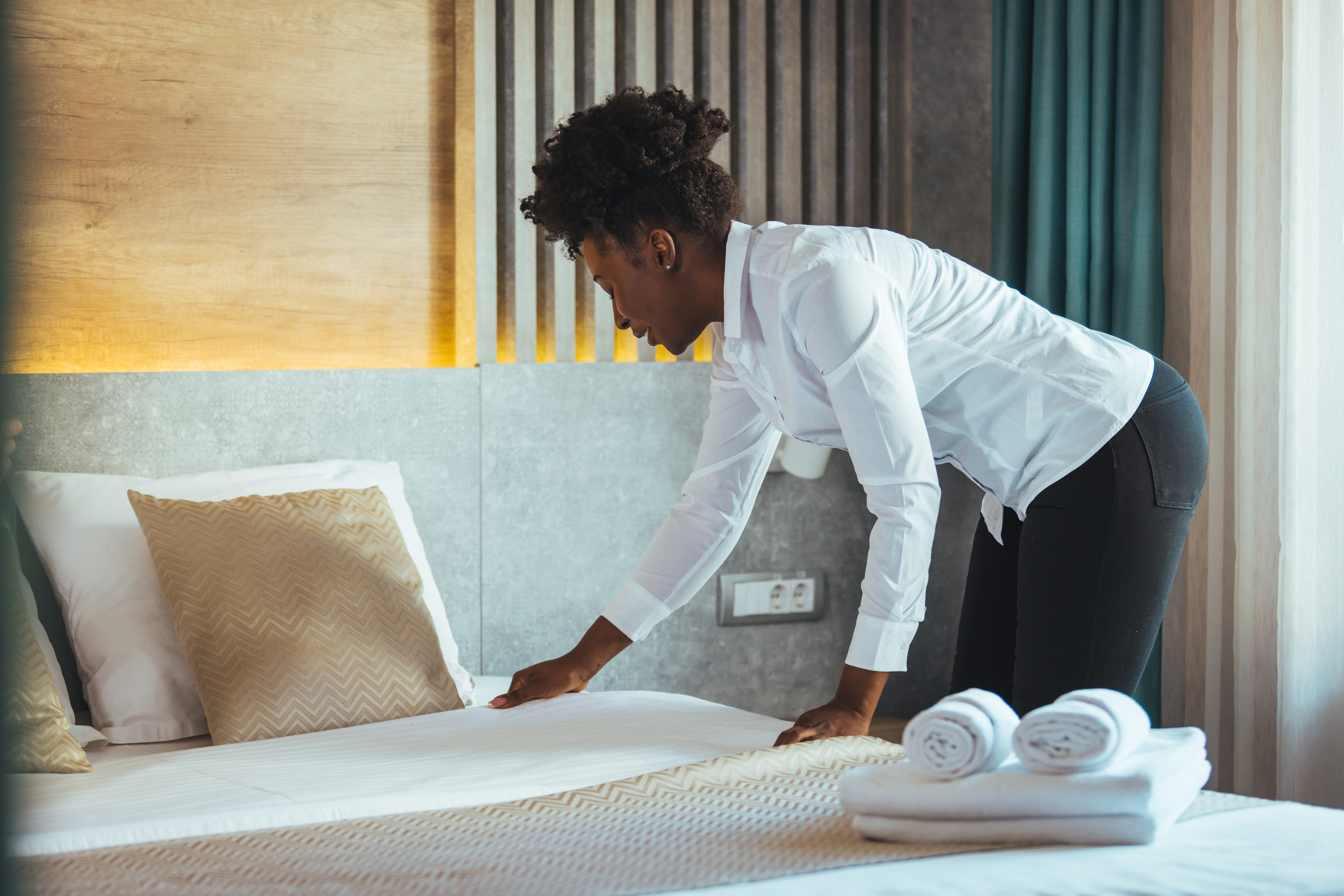 Maid making bed in hotel room. Housekeeper Making Bed. Maid making bed in hotel room. Staff Maid Making Bed. African housekeeper making bed.