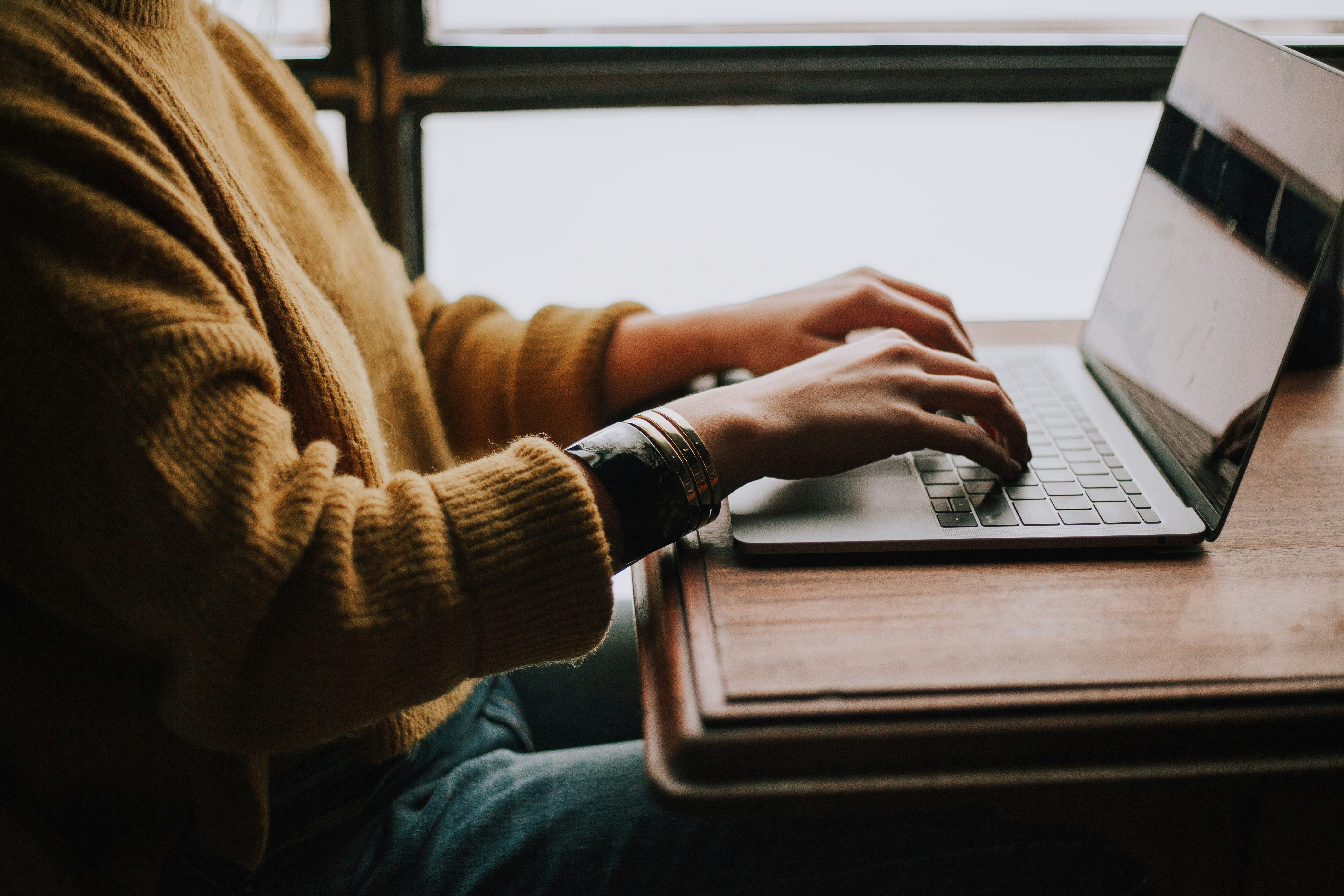Someone sitting at a table working on a laptop.
