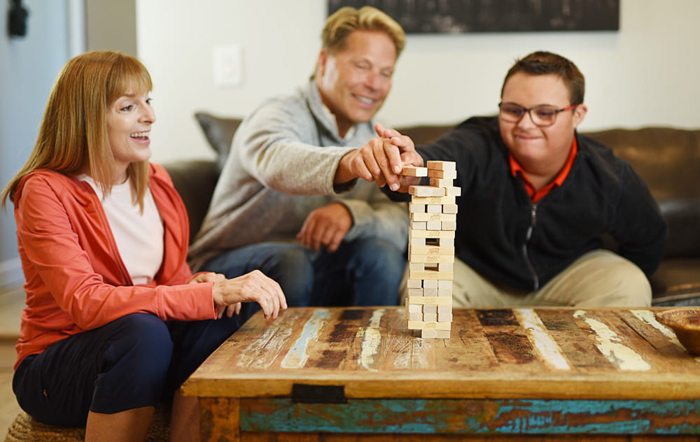 Three people playing Jenga on their coffee table