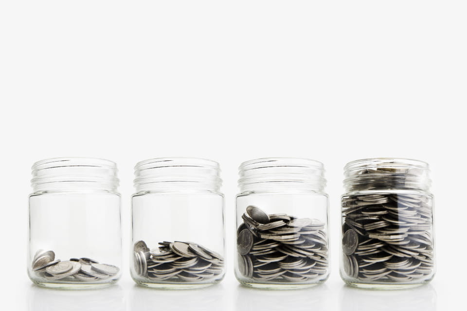 Four glass jars of coins with progressively more in them