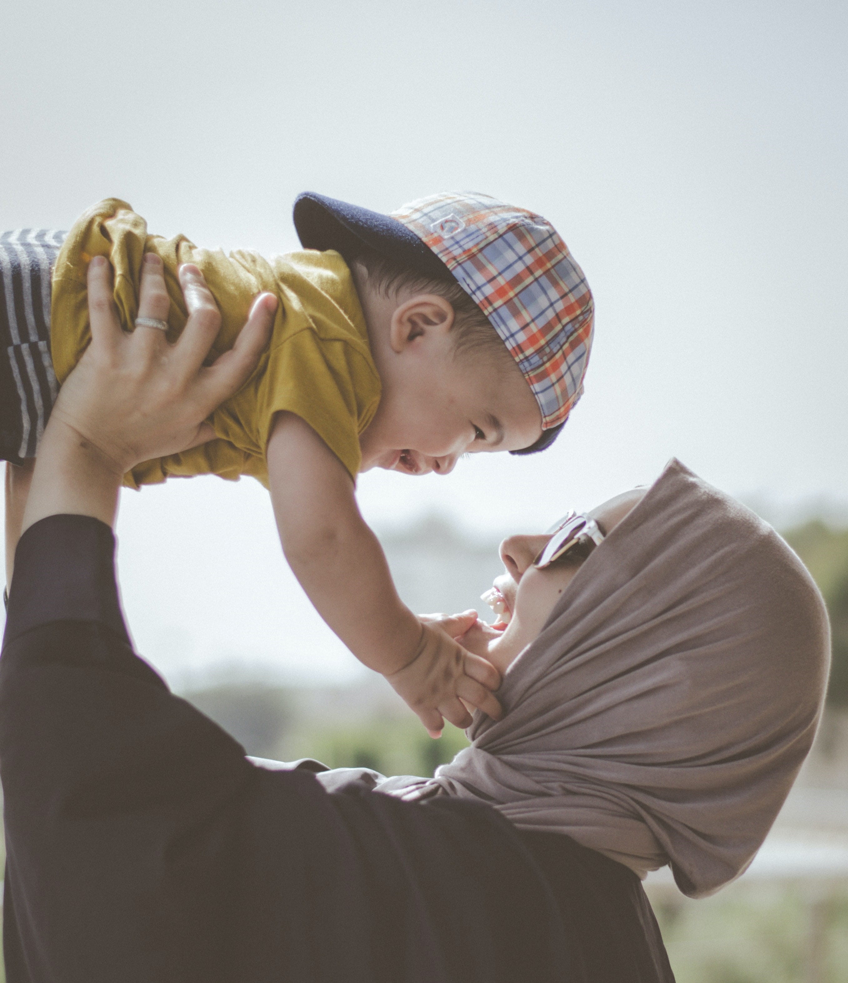 caregiver holding baby in air smiling