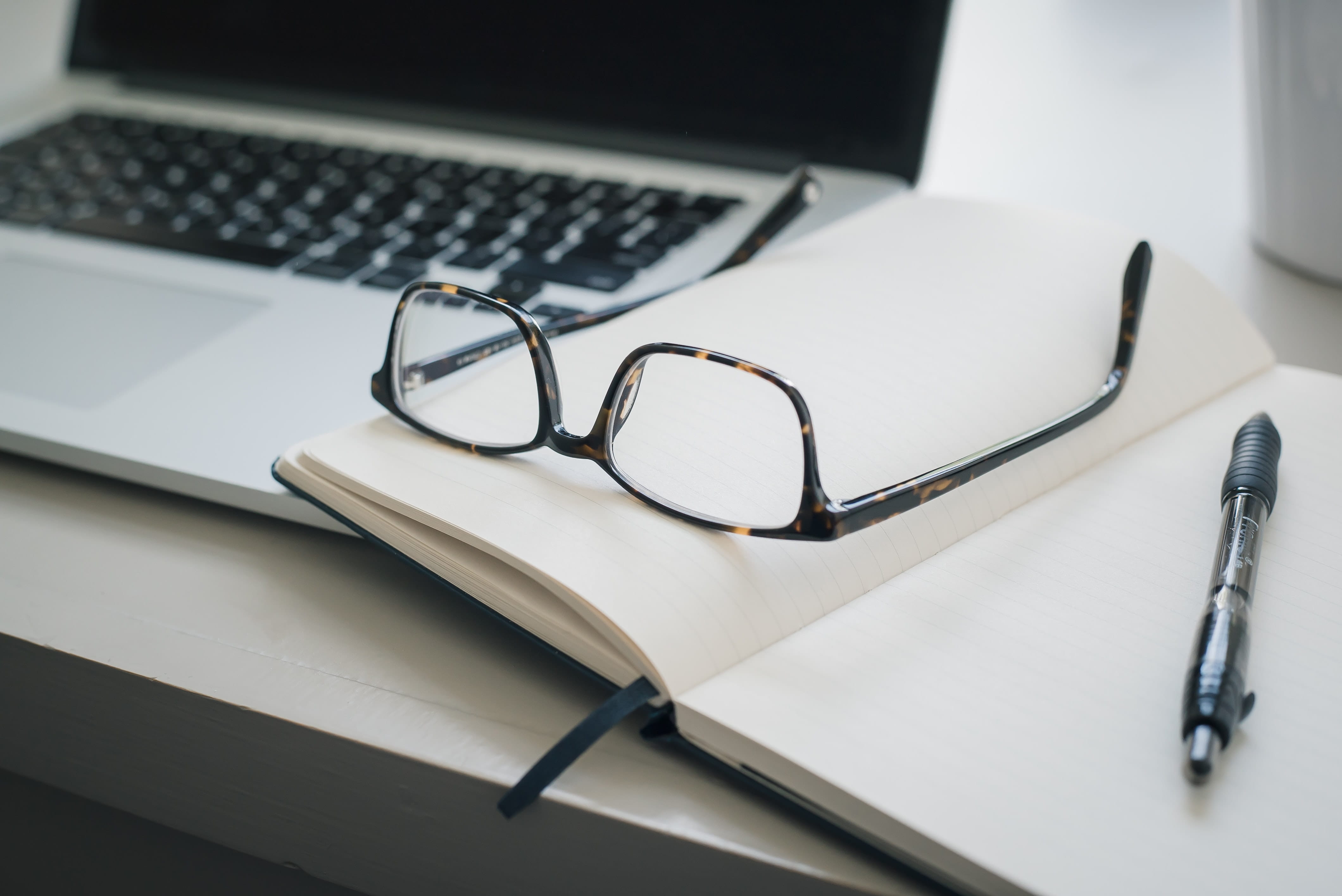 computer notepad and glasses and pen on desk