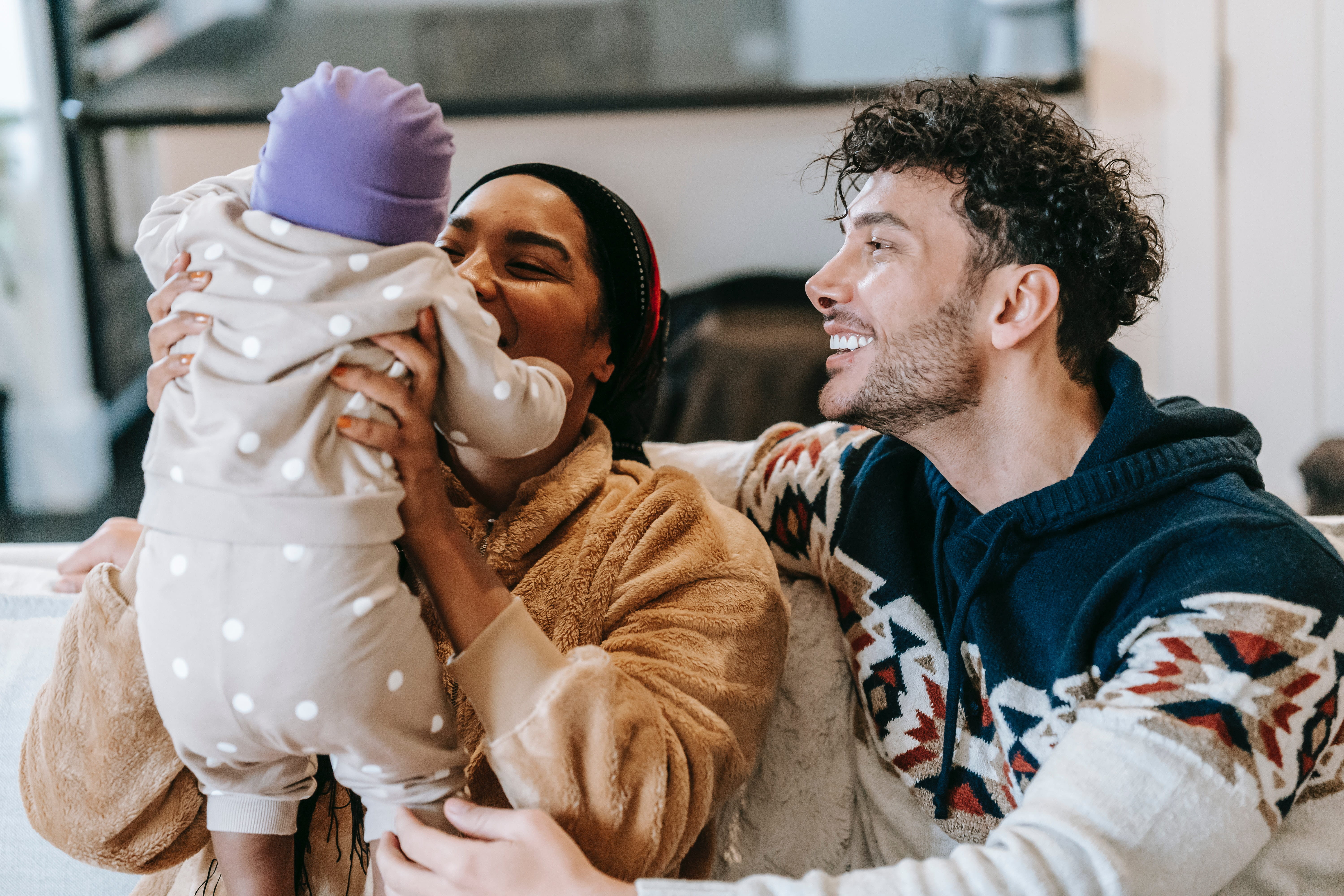 two people holding a baby while on a couch