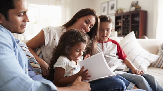 mom and dad on couch at home reading to two young children