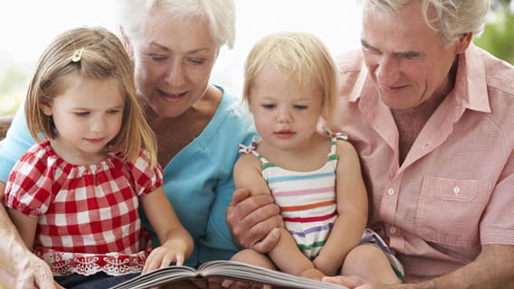 grandmother and grandfather reading to young granddaughters