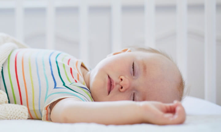 baby sleeping on back in a crib