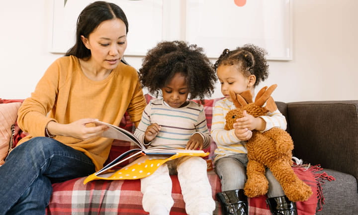 provider in home care setting reading to two toddler girls