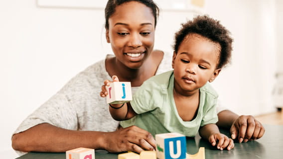 mother holding and smiling at child playing with blocks