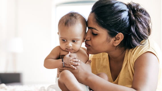 mom holding and kissing infant 