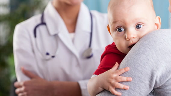 bright eyed baby in parents arms while doctor talks to parent