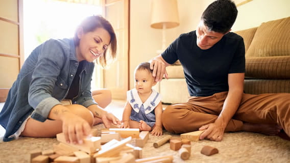 mom dad and infant playing with wooden blocks