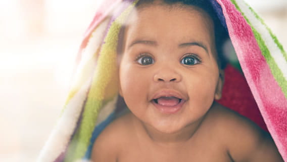 happy baby under colorful blanket