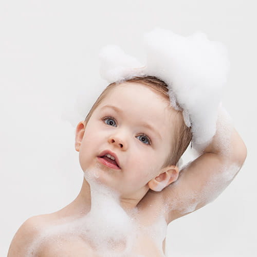 toddler lathering up hair with soap suds