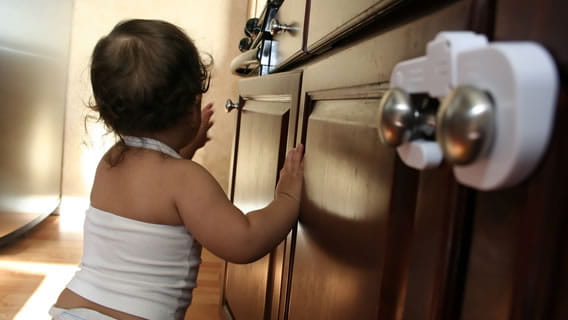 baby next to cabinets with safety closures