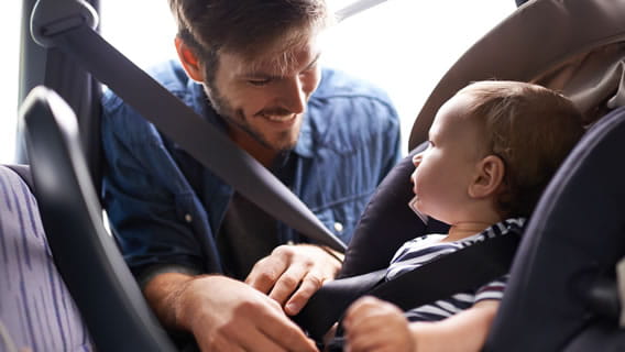 dad strapping baby in car seat