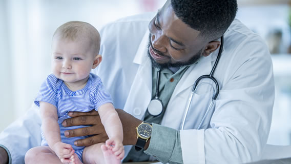 doctor holding up smiling baby