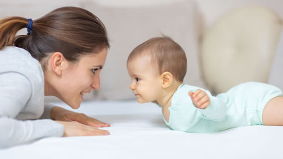 mom looking face to face at baby pulling up from resting on tummy