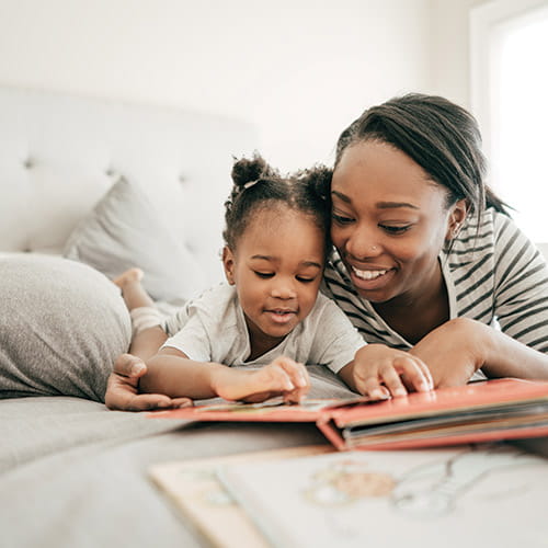 mom and daughter laying on bed reading