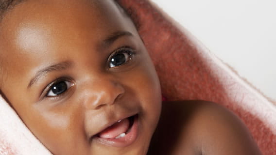 baby wrapped in blanked smiling